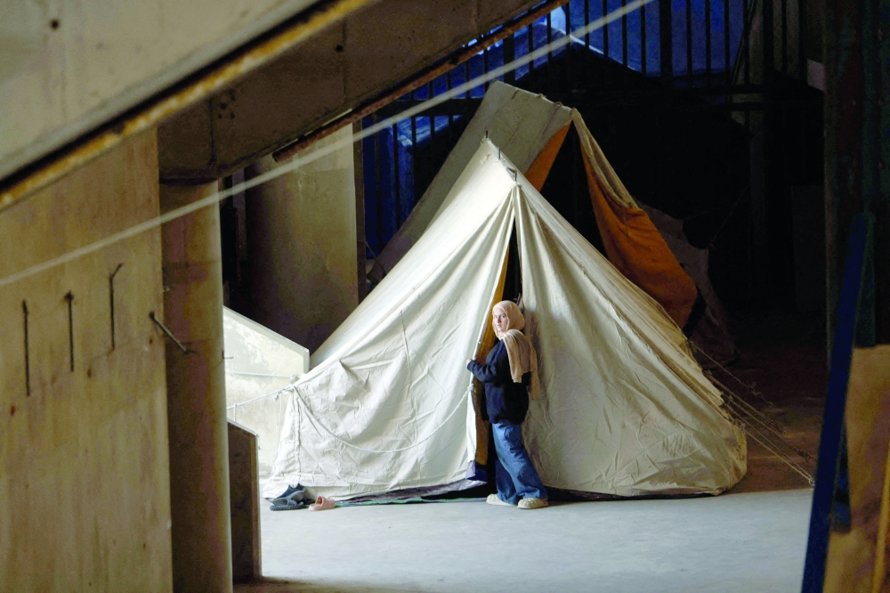 A displaced woman stands next to her tent inside the Camille Chamoun Sports City stadium, in Beirut. — AFP