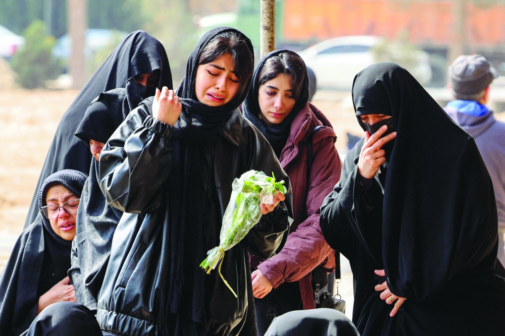 Women mourners react before the grave of a person killed in recent air strikes, in Tehran. — AFP