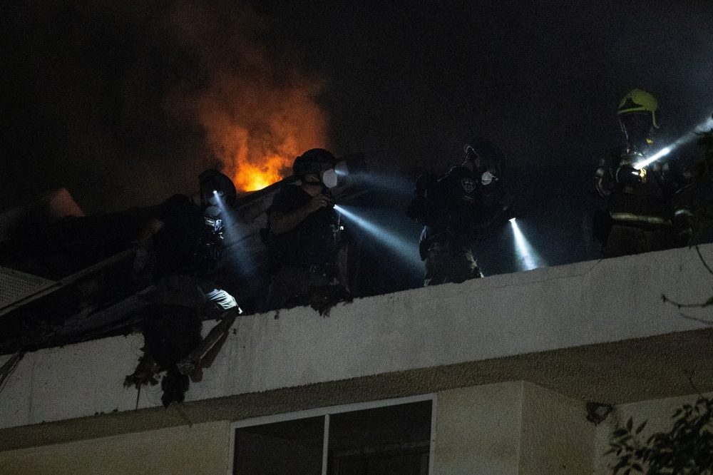Rescue workers inspect a residential building that was hit following an Iranian missile strike, amid the U.S.-Israeli conflict with Iran