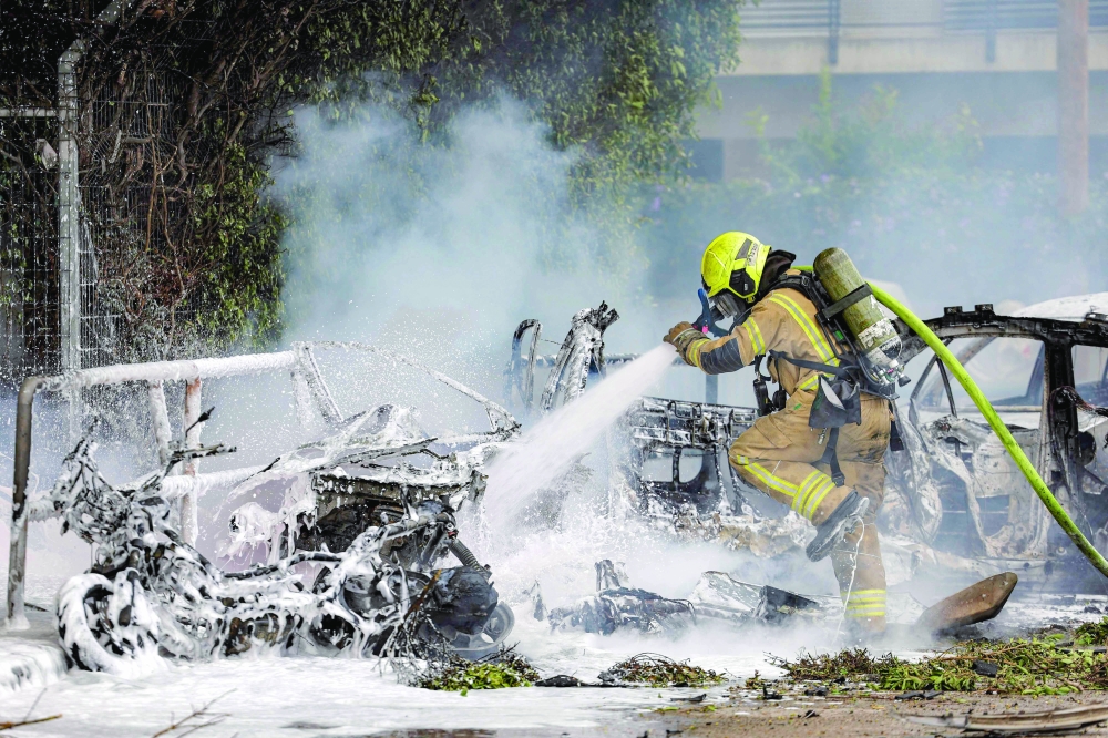 A firefighter extinguishes a blaze following a projectile impact, in southern Tel Aviv. — AFP