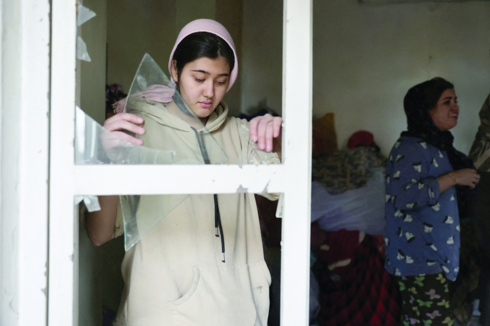 A woman takes out a broken glass from a window at her house that was damaged by a strike in Tehran, Iran, on Sunday. - Reuters