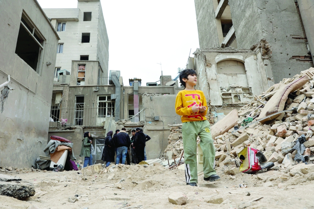 A boy stands near a house that was damaged by a strike, amid the US-Israeli conflict with Iran, in Tehran, Iran, on Sunday. - Reuters