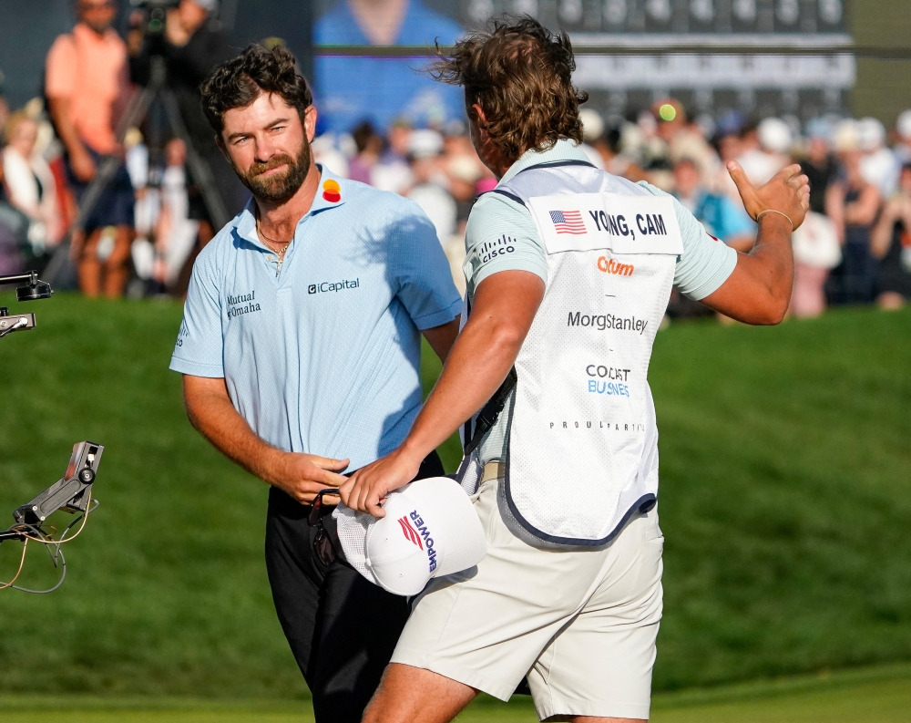  Cameron Young and his caddie Kyle Sterbinsky embrace on the 18th green during the final round of THE PLAYERS Championship golf tournament 