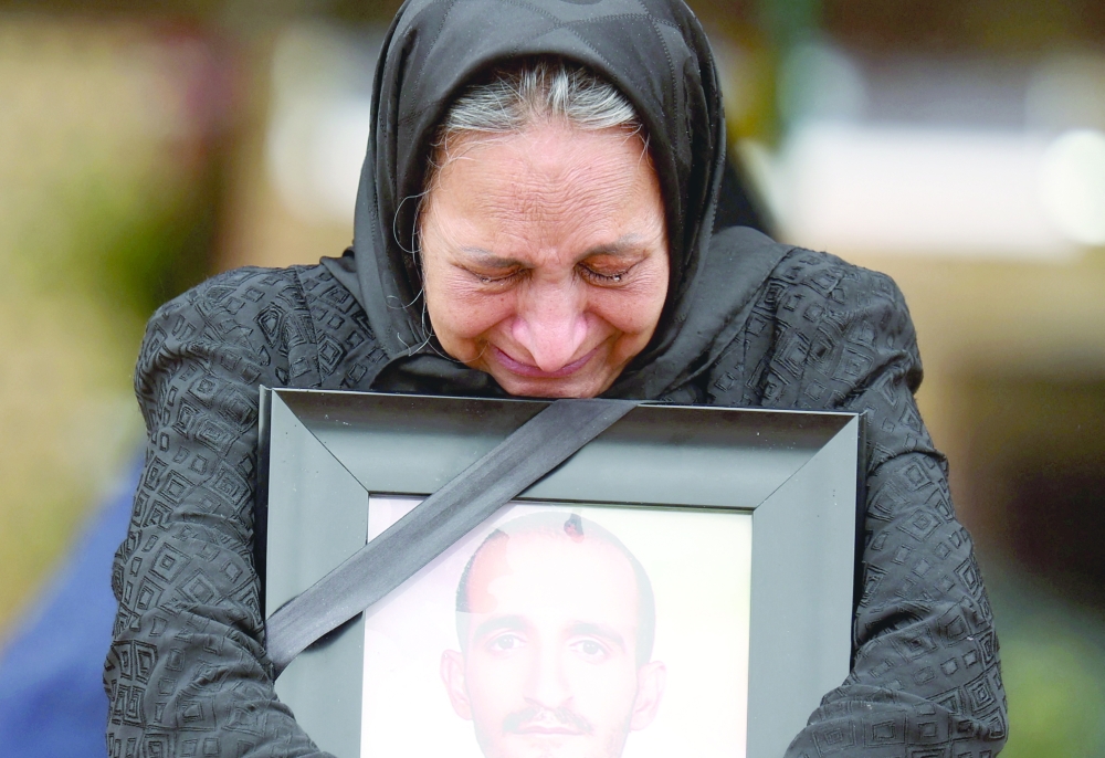 An Iraqi woman reacts while standing near the grave of her son, who was killed in strikes, amid the US-Israeli conflict with Iran, at Behesht-e Zahra cemetery, in Tehran, Iran, on Monday. - Reuters