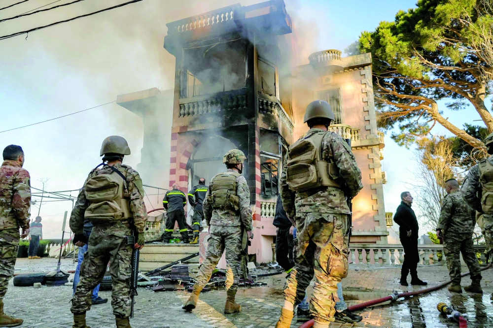 Lebanese army soldiers and civil defence members inspect a building that burned following Israeli bombardment. — AFP