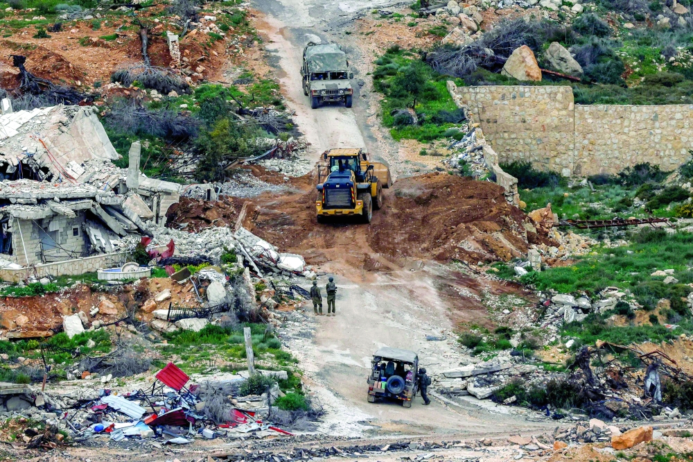 Israeli soldiers and a bulldozer conduct an operation in a southern Lebanese village along the border. — AFP