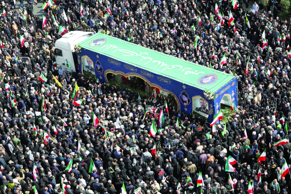 People gather around the coffin of Iranian security chief Ali Larijani during a funeral for Larijani and victims of the IRIS Dena warship at Enghelab Square in Tehran, Iran, on Wednesday. - Reuters