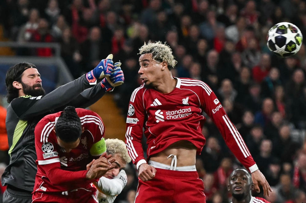 Liverpool's Brazilian goalkeeper #01 Alisson (L) makes a save next to Liverpool's French forward #22 Hugo Ekitike
