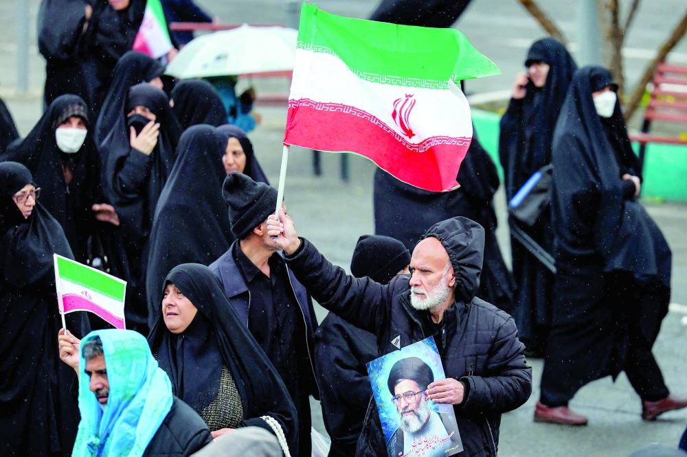 A mourner holds an Iranian flag and a picture of Iran's slain leader Ayatollah Ali Khamenei while marching with others during the funeral ceremony for Iran's slain intelligence minister Esmail Khatib and his family after the noon prayers in Tehran. 
- AFP
