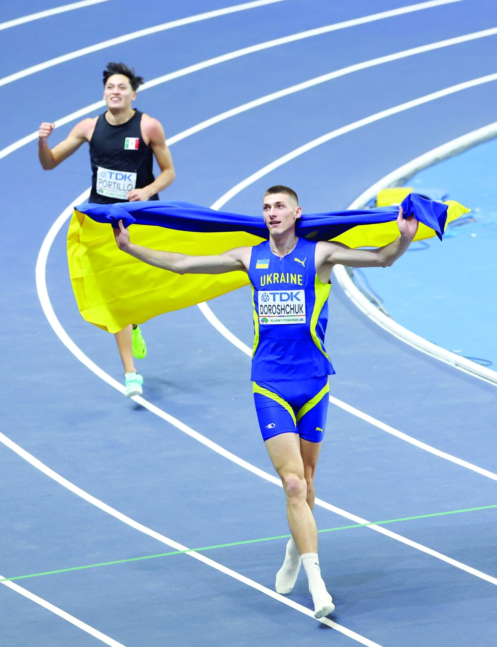 Athletics - World Indoor Championships - Kujawsko-Pomorska Arena, Torun, Poland - March 21, 2026 Ukraine's Oleh Doroshchuk celebrates with his national flag after winning gold in the men's high jump final as Mexico's Erick Portillo celebrates after winning silver REUTERS/Bernadett Szabo