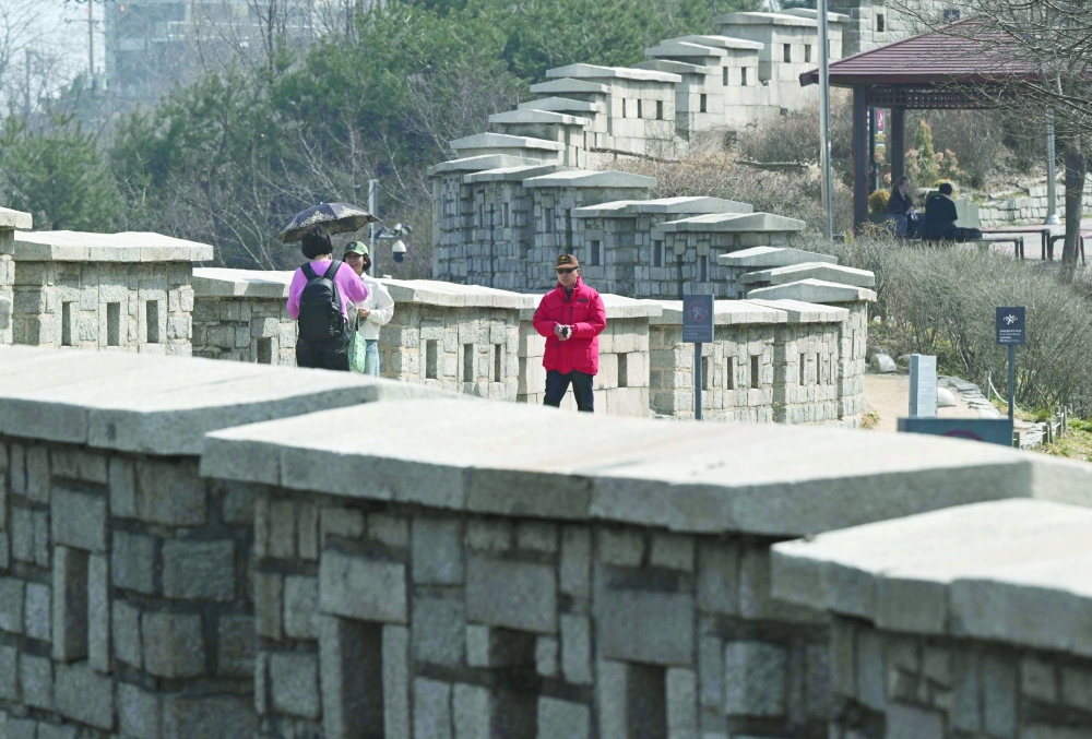 People walk along the fortress wall at Naksan Park in Seoul. — AFP