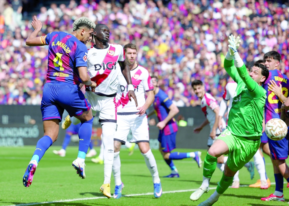 Barcelona's Uruguayan defender #04 Ronald Federico Araujo da Silva scores his team's first goal in spite of Rayo Vallecano's Argentine goalkeeper #13 Augusto Batalla during the Spanish league football match between FC Barcelona and Rayo Vallecano de Madrid at Camp Nou Stadium in Barcelona on March 22, 2026. (Photo by Josep LAGO / AFP)
