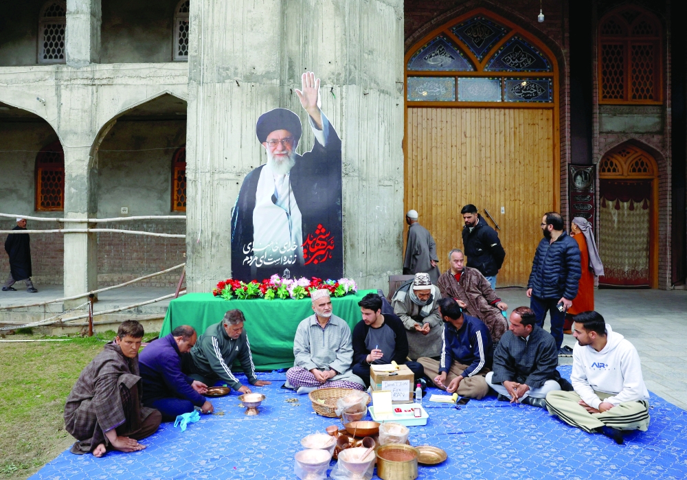 Kashmiri volunteers sit outside a fund collection centre in Srinagar. — Reuters