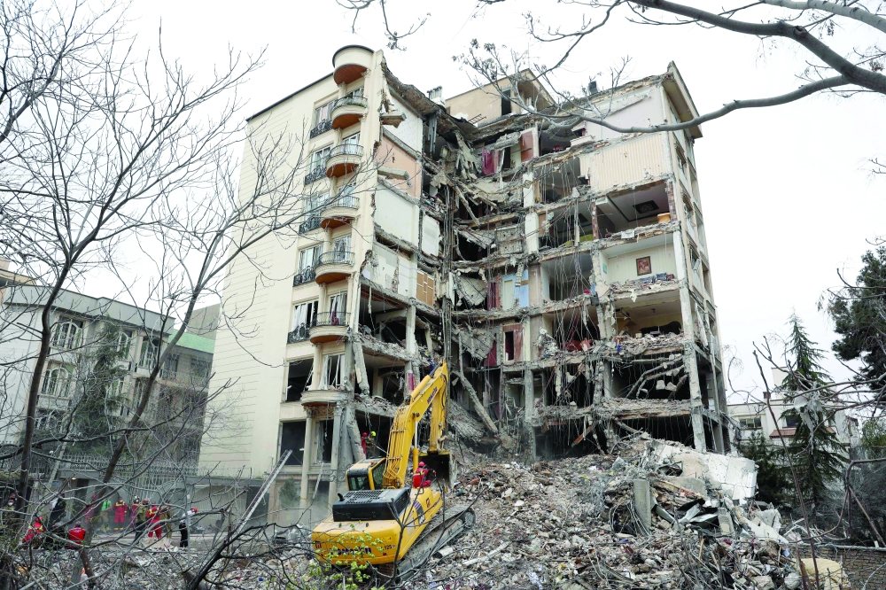 An excavator clears rubble from a destroyed residential building in northern Tehran. — AFP
