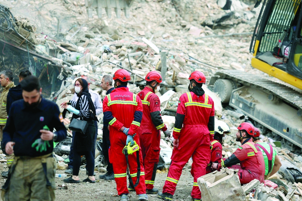 Iranian rescuers gather at a destroyed residential building as a search is carried out, Tehran. — AFP