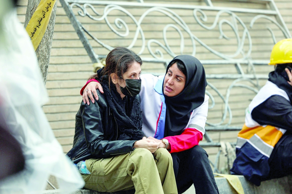 A member of the Iranian Red Crescent comforts a resident of a destroyed apartment block in northern Tehran on Monday. — AFP