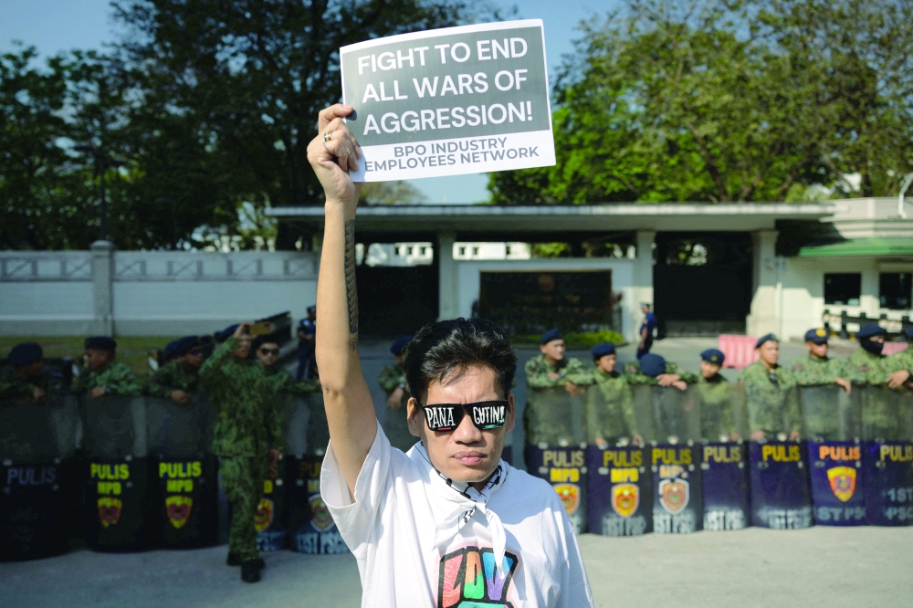 A Filipino activist holds a sign as they protest outside the US Embassy, in Manila. — Reuters