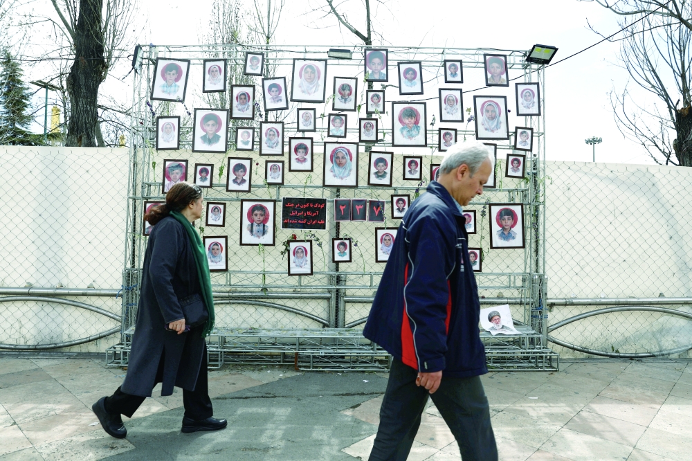 People walk next to pictures of child victims killed in strikes, in Tehran. — Reuters