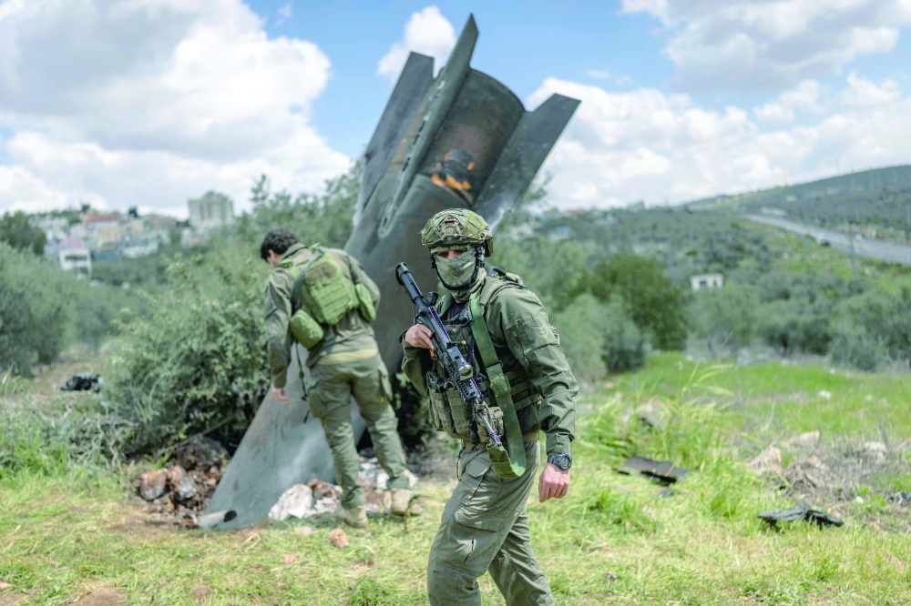 Israeli soldiers arrive to check an Iranian missile fragment that landed in the West Bank. — AFP
