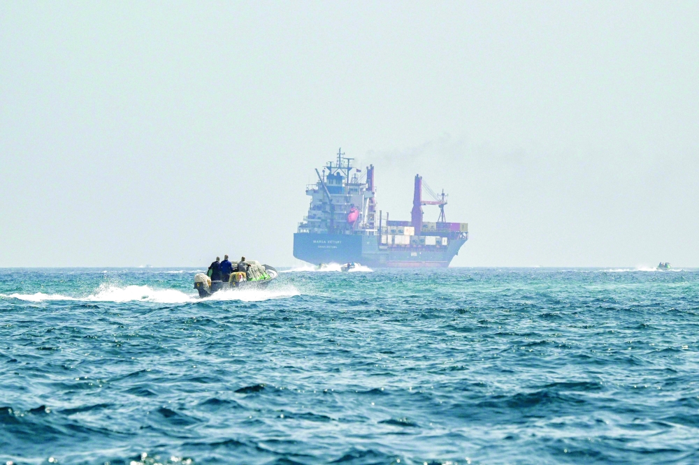 A boat approaches a container ship while crusing in the waters of the Strait of Hormuz. — AFP