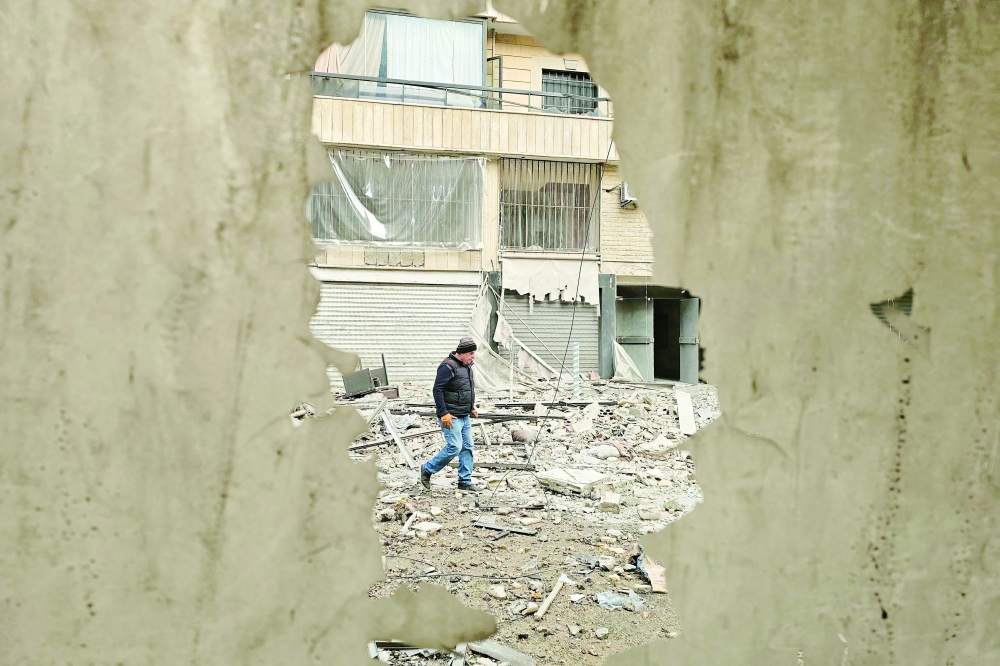 A man walks along a street strewn with building debris, in Beirut. — AFP