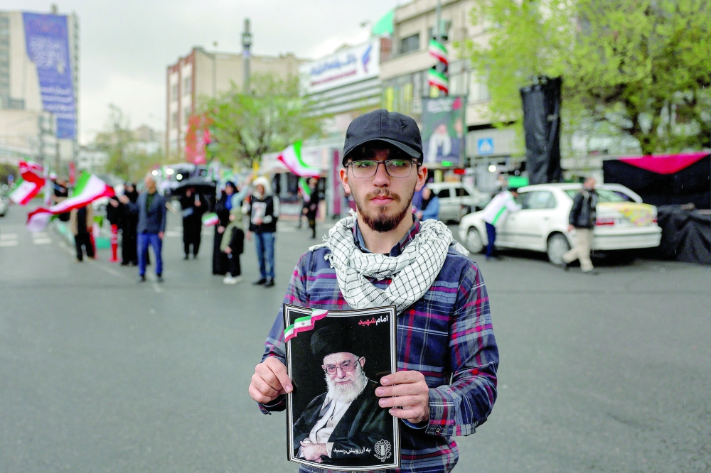 A man holds a picture of Iran's late Supreme Leader Ali Khamenei along Enghelab Square in central Tehran on Wednesday. — AFP