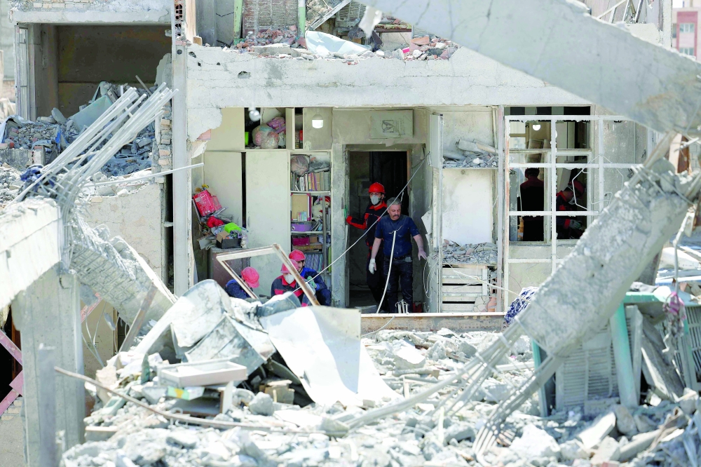 Firefighters look for victims and inspect damage at a residential building in southern Tehran on Friday. — AFP