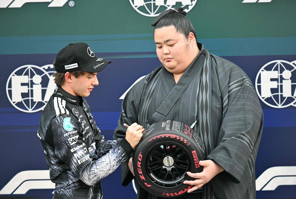Mercedes' Italian driver Kimi Antonelli receives a pole position award from Japanese sumo wrestler Kotozakura Masakatsu II