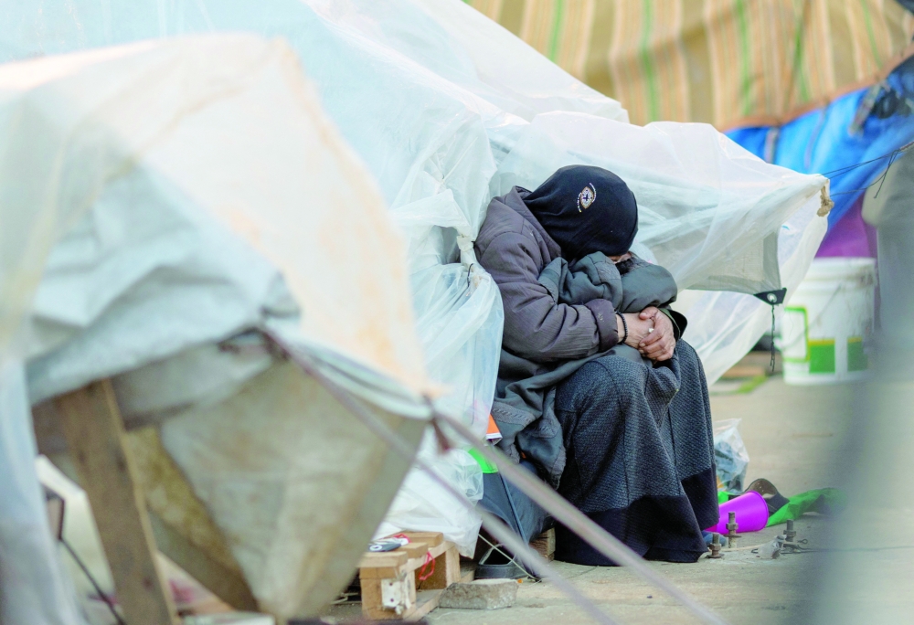 A woman holds a baby as she sits outside her family tent, at a temporary encampment for displaced people, in Beirut. — Reuters