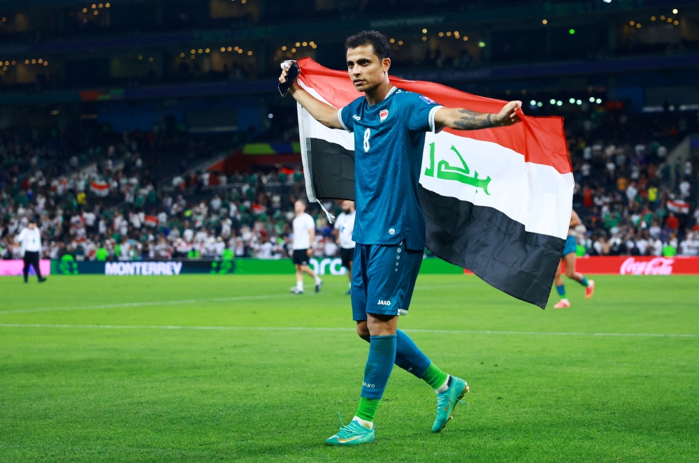  Iraq's Ibrahim Bayesh celebrates with the national flag after qualifying for FIFA World Cup  