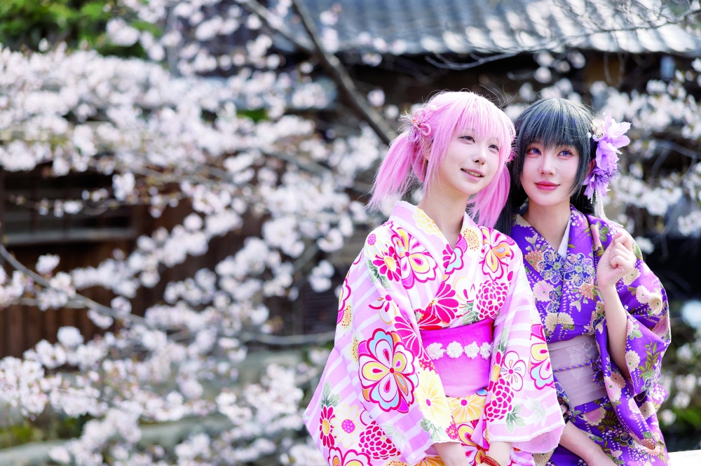 Tourists from abroad wearing kimonos pose for a souvenir photo with blooming cherry blossoms in Kyoto, Japan, March 28, 2026. REUTERS/Manami Yamada