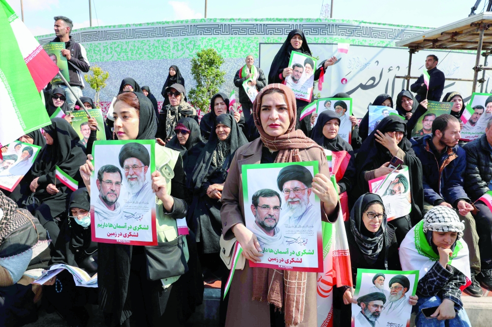 People hold portraits of Iran's slain supreme leader Ayatollah Ali Khamenei (R) and Alireza Tangsiri (L), commander of the Iranian Revolutionary Guards' navy during his funeral, at Enghelab Square in Tehran. — AFP 