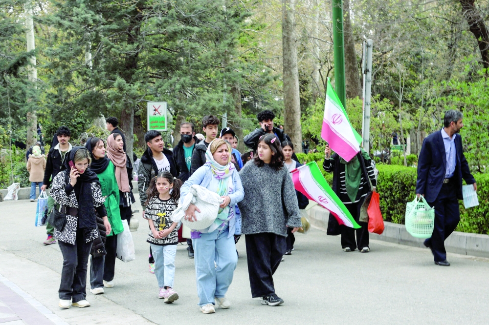 Iranians walk through Tehran's Melat park during 'Sizdeh Bedar' (Nature Day), the 13th day after the Nowruz Persian New Year, when people traditionally picnic outdoors with family and friends. - AFP
