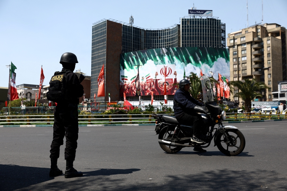 A member of a police force stands guard on a street, amid the U.S.-Israeli conflict with Iran, in Tehran