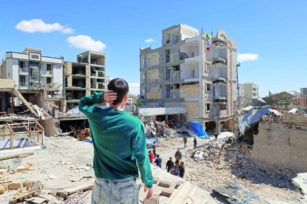 A man looks at the residential buildings that were damaged by recent strikes in Vahdat town in Karaj, southwest of Tehran on Friday. &mdash; AFP