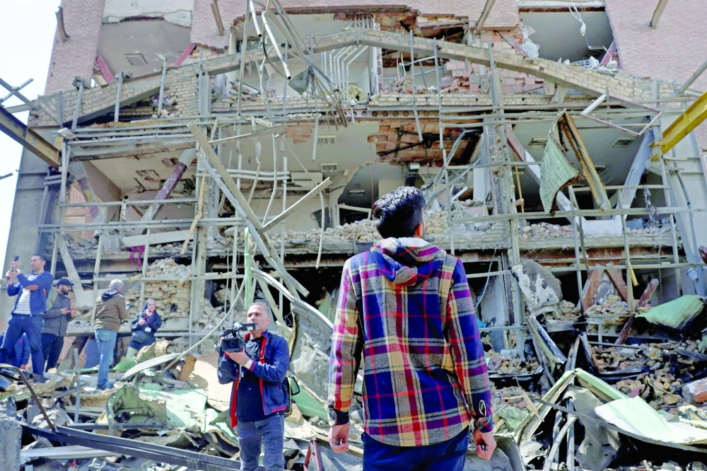 Media representatives gather around the damaged building of the Shahid Beheshti University following a strike, in Tehran. — AFP