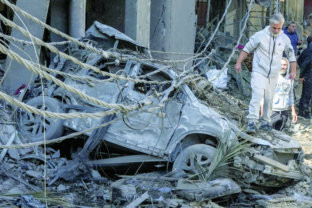 A man stands on a destroyed vehicle at the site of Sunday's Israeli strike on a building in Beirut on Monday. — AFP