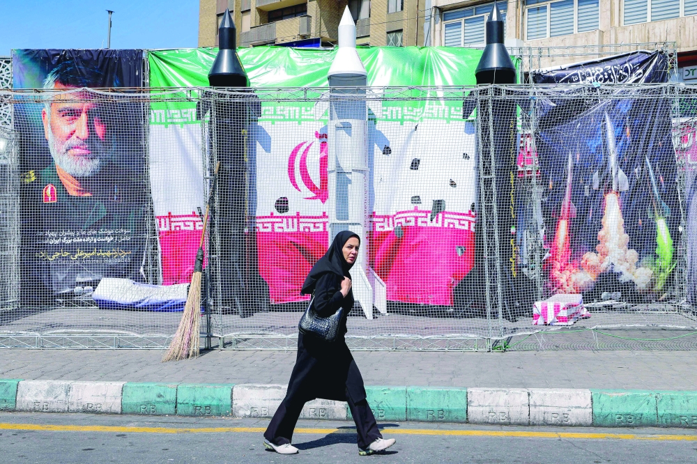 A woman walks past mockups of Iranian missiles along Valiasr Square in Tehran on Monday. — AFP 