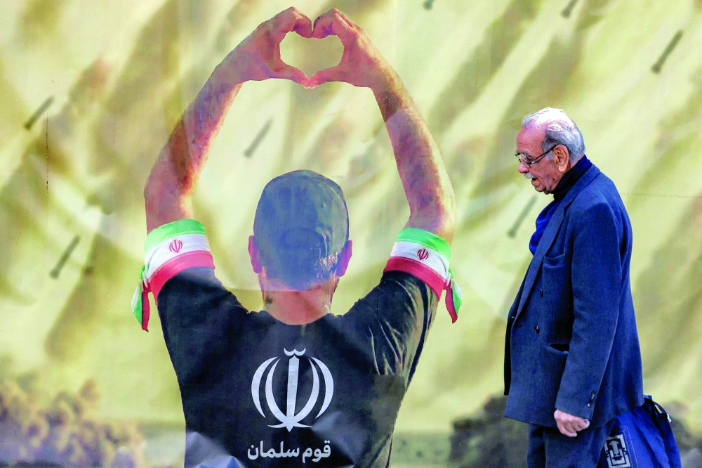 A banner depicting a man holding up a heart gestures before missiles being fired, in Tehran on Monday. - AFP
