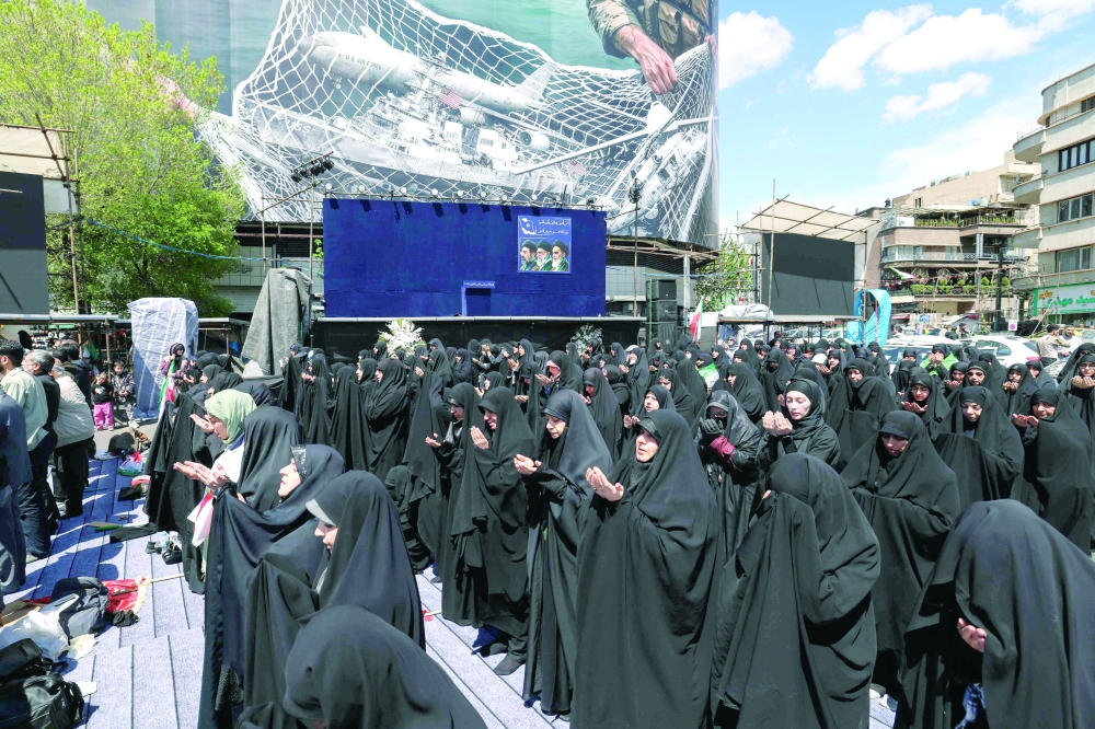Iranians perform noon prayers as they gather in Tehran's Revolution Square. — AFP