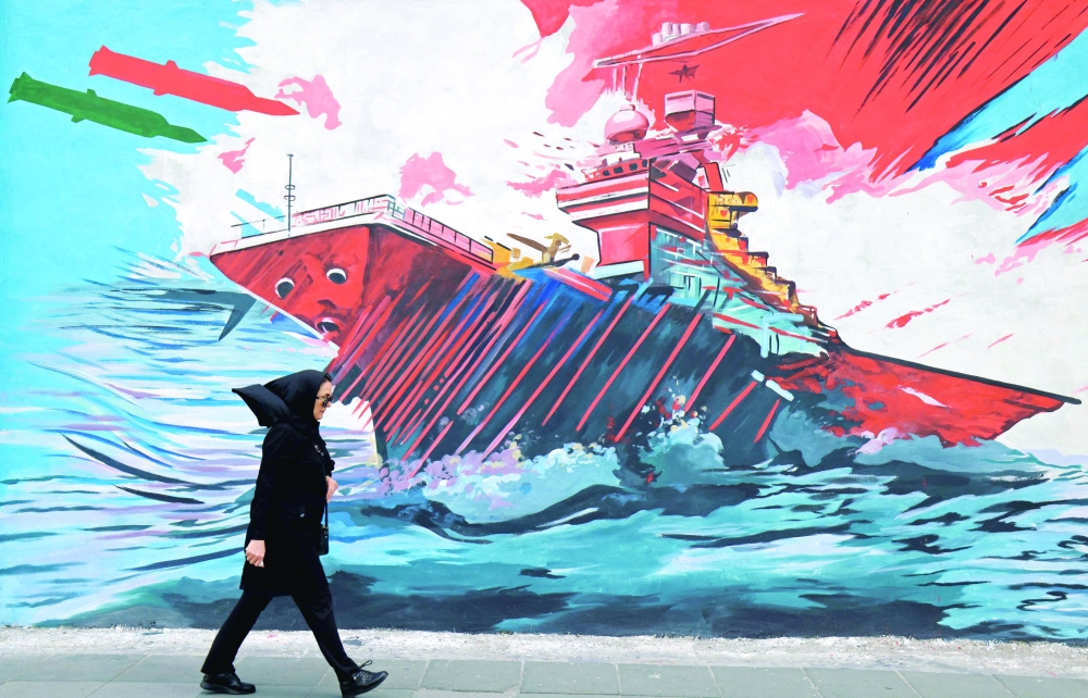 A woman walks past a mural in Tehran on Wednesday. - AFP