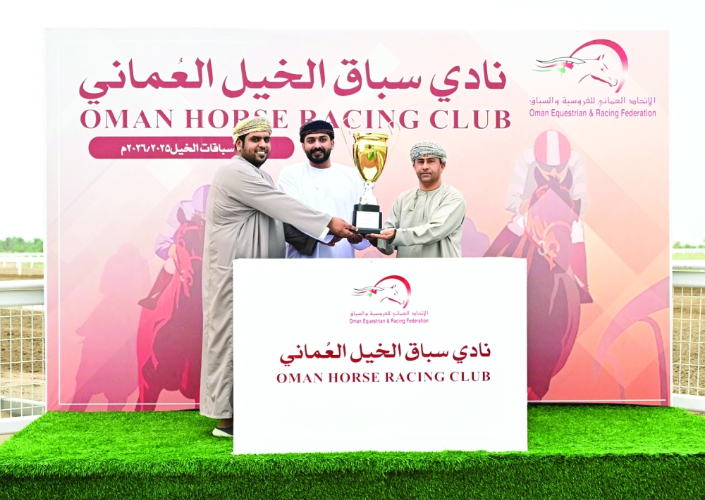Ahmed bin Ibrahim al Balushi (L), trainer of RB Epic which won the ninth race, receives the trophy.