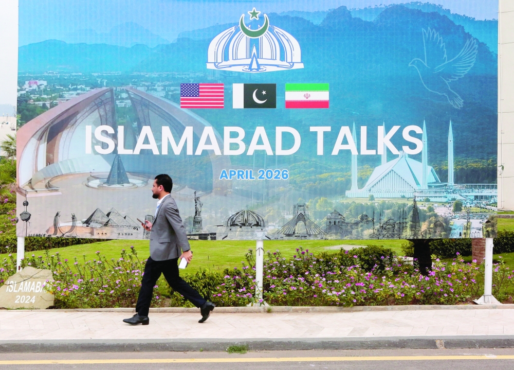 A man walks past a billboard near the media centre in Islamabad on Saturday. — Reuters