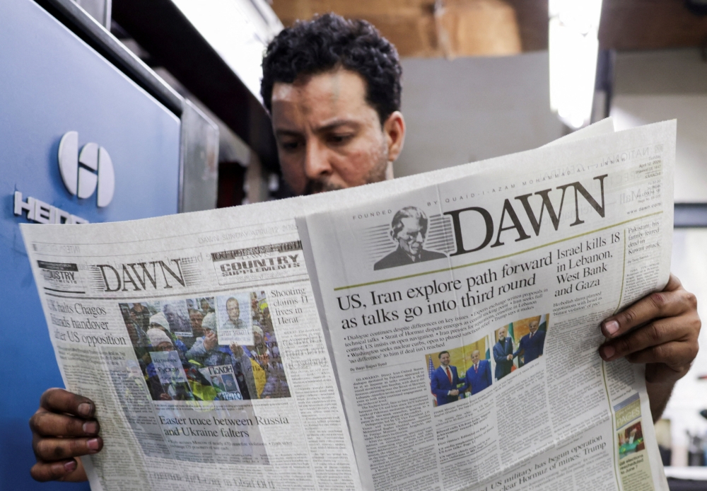 A worker reads a freshly printed newspaper featuring a headline about the U.S. and Iran peace talks in Islamabad, at a printing press in Karachi, Pakistan, April 12, 2026. REUTERS/Insiya Syed