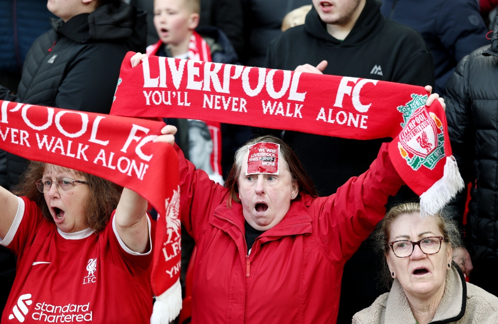  A Liverpool fan has a sticker on her forehead protesting ticket prices as fans hold scarves up in the stands before the match   