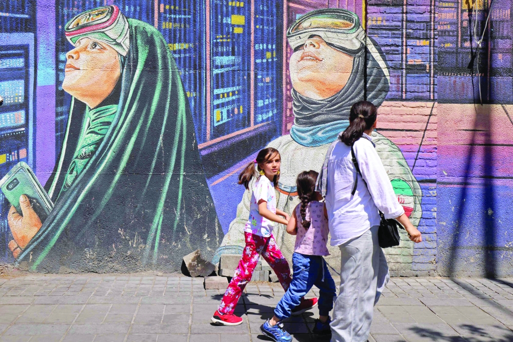 People walk past a wall mural along the roadside in Tehran. — AFP