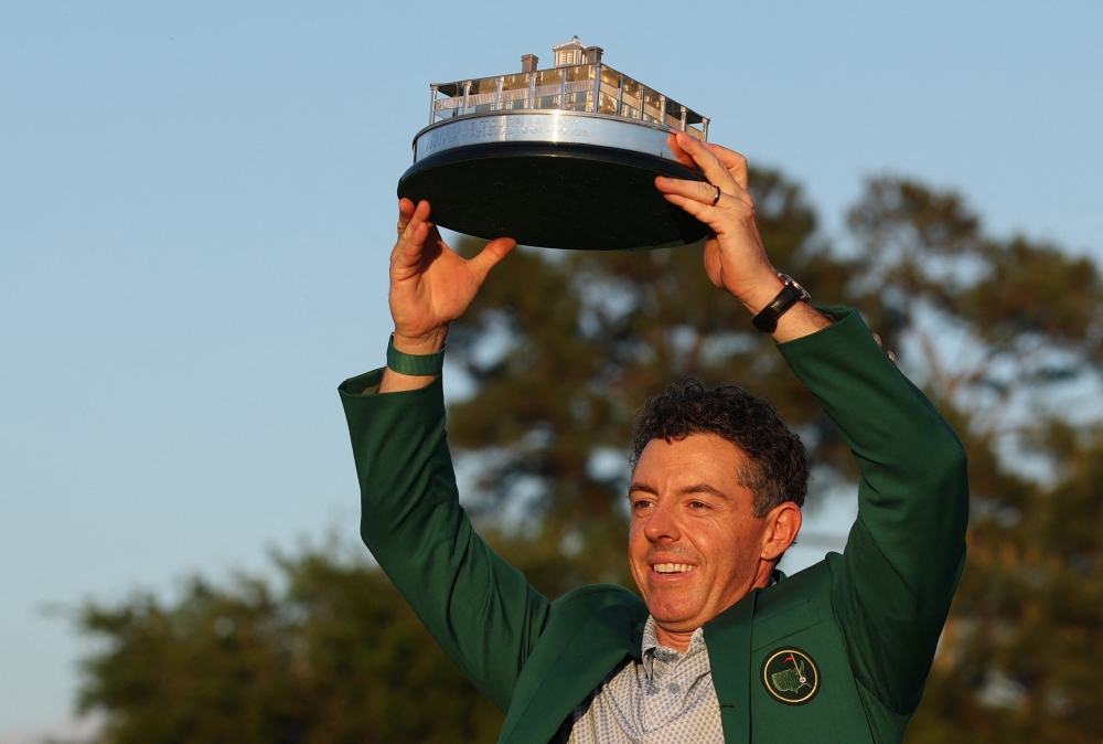 Northern Ireland's Rory McIlroy celebrates with his green jacket and the trophy after winning The Masters  