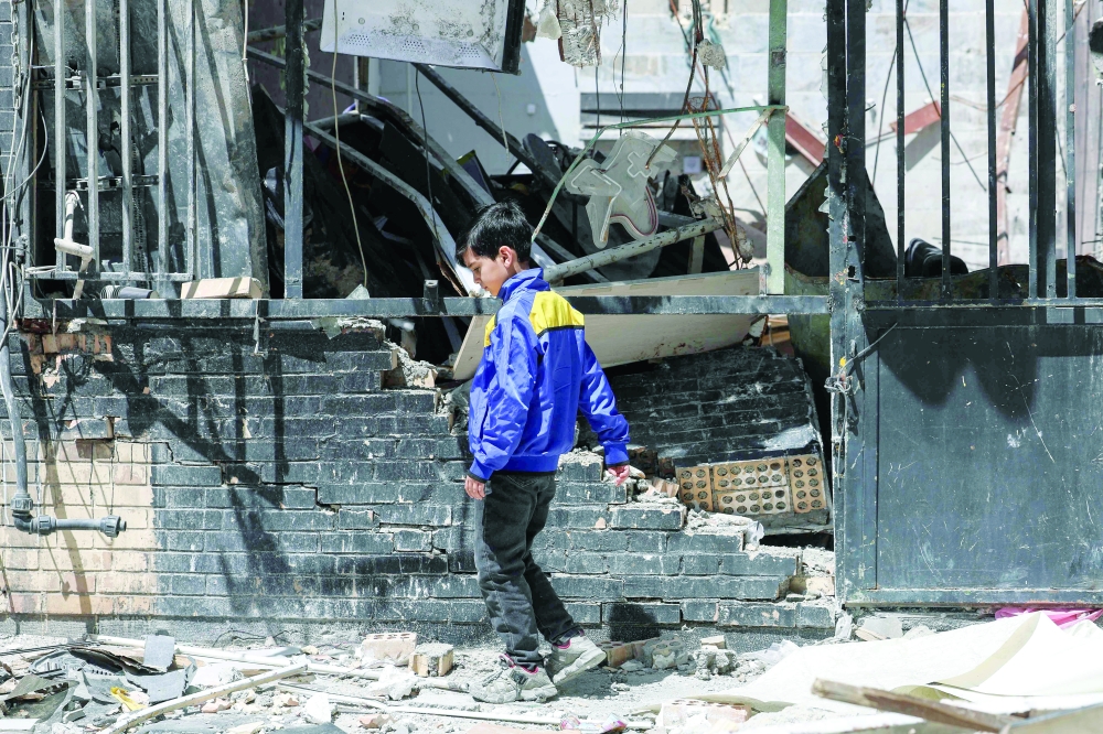 An Iranian boy walks amid the debris of a residential building hit by US-Israel air strikes, in Tehran. — AFP