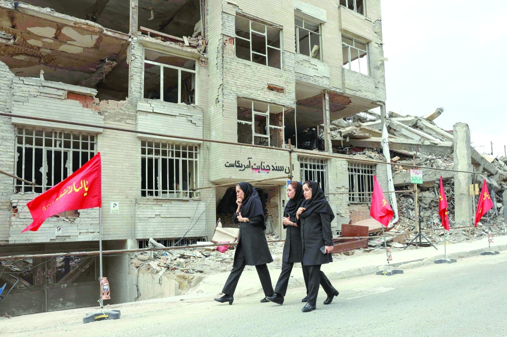 Iranian women walk past a residential building destroyed in a US-Israeli air strike, in Tehran. — Reuters