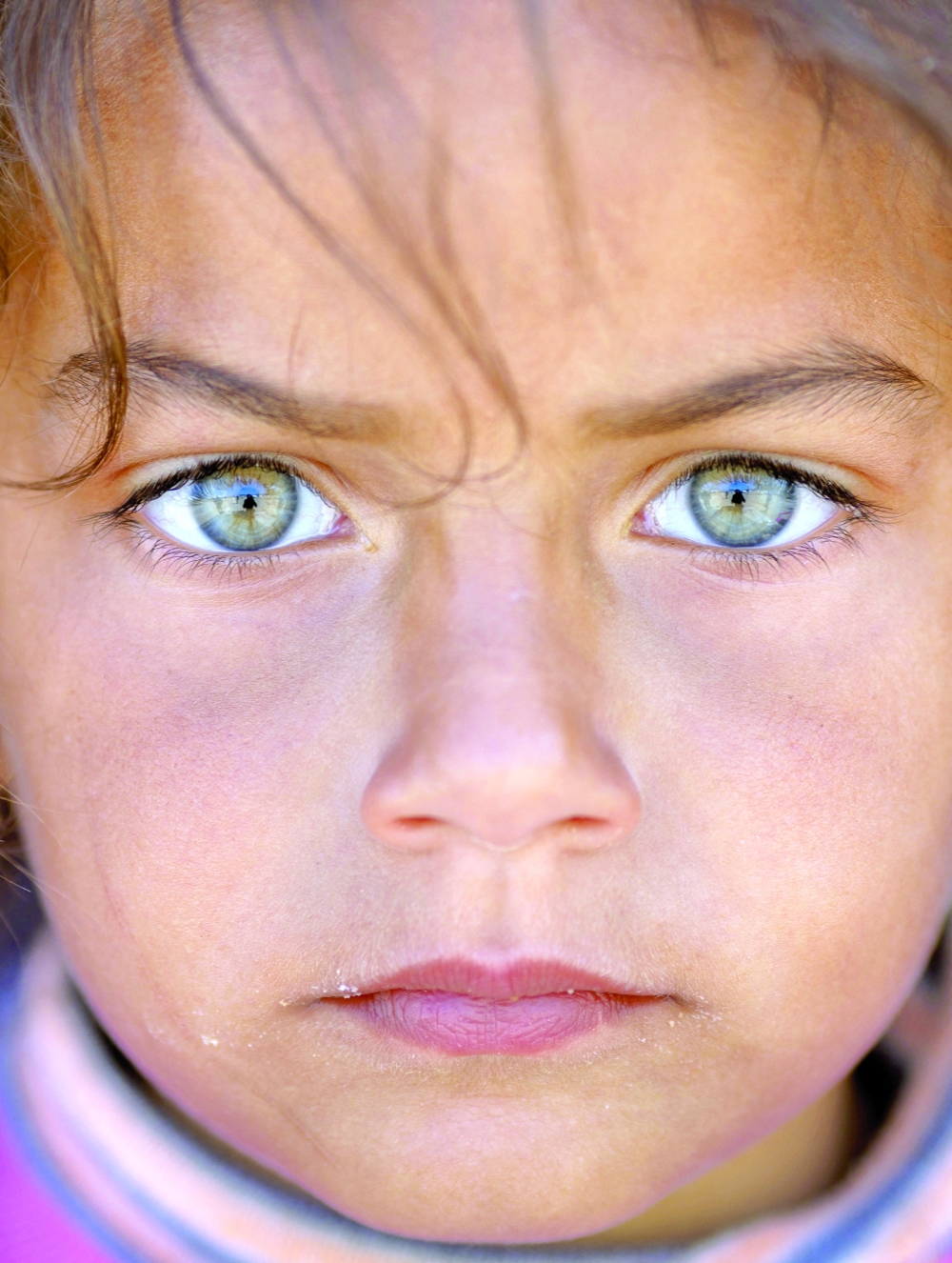 A displaced girl, who fled her home following Israeli evacuation orders, sits behind a truck at a makeshift encampment in Beirut, Lebanon, on Tuesday. — Reuters